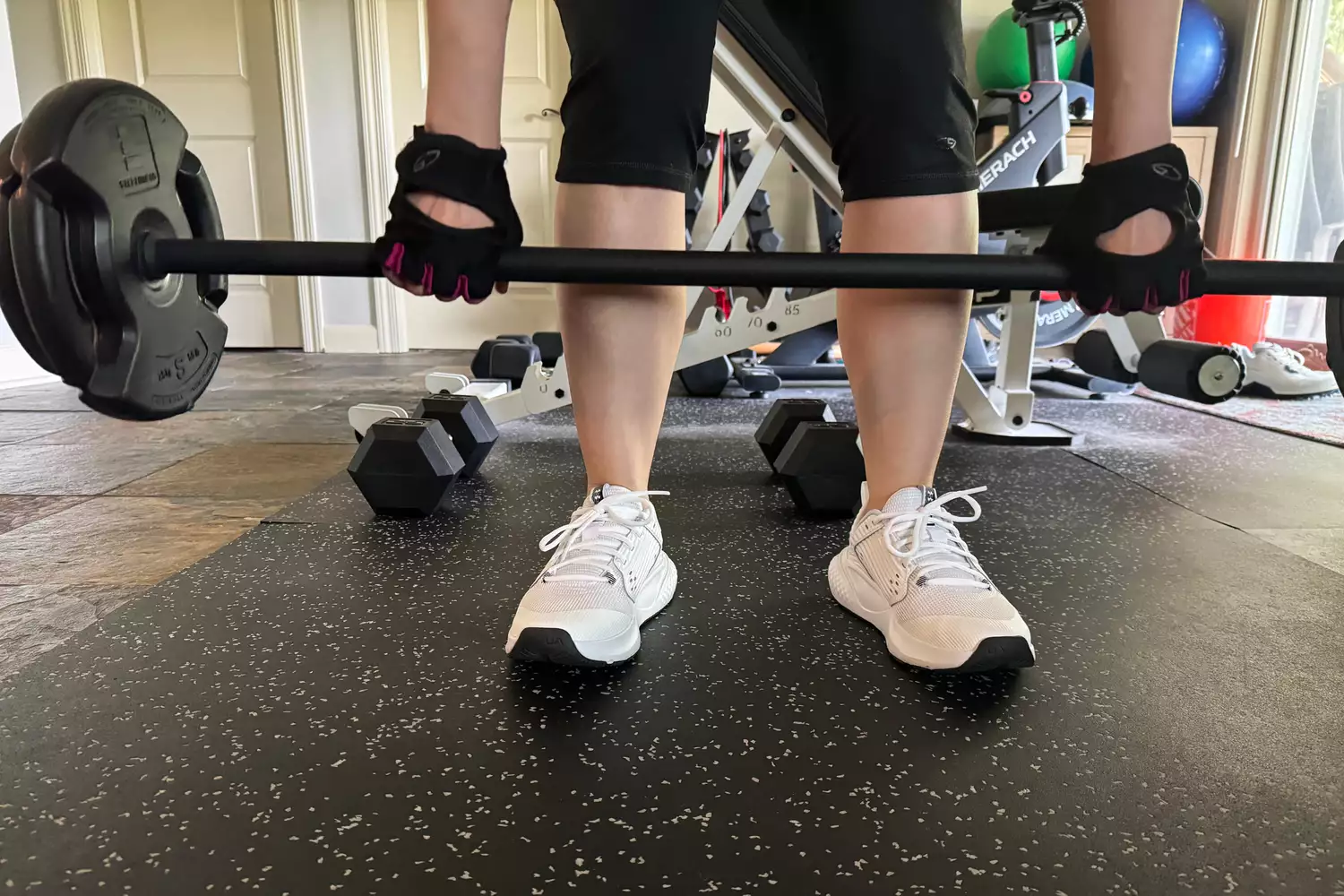 A person lifts a barbell while wearing the Under Armour Women's UA Commit 4 Training Shoes