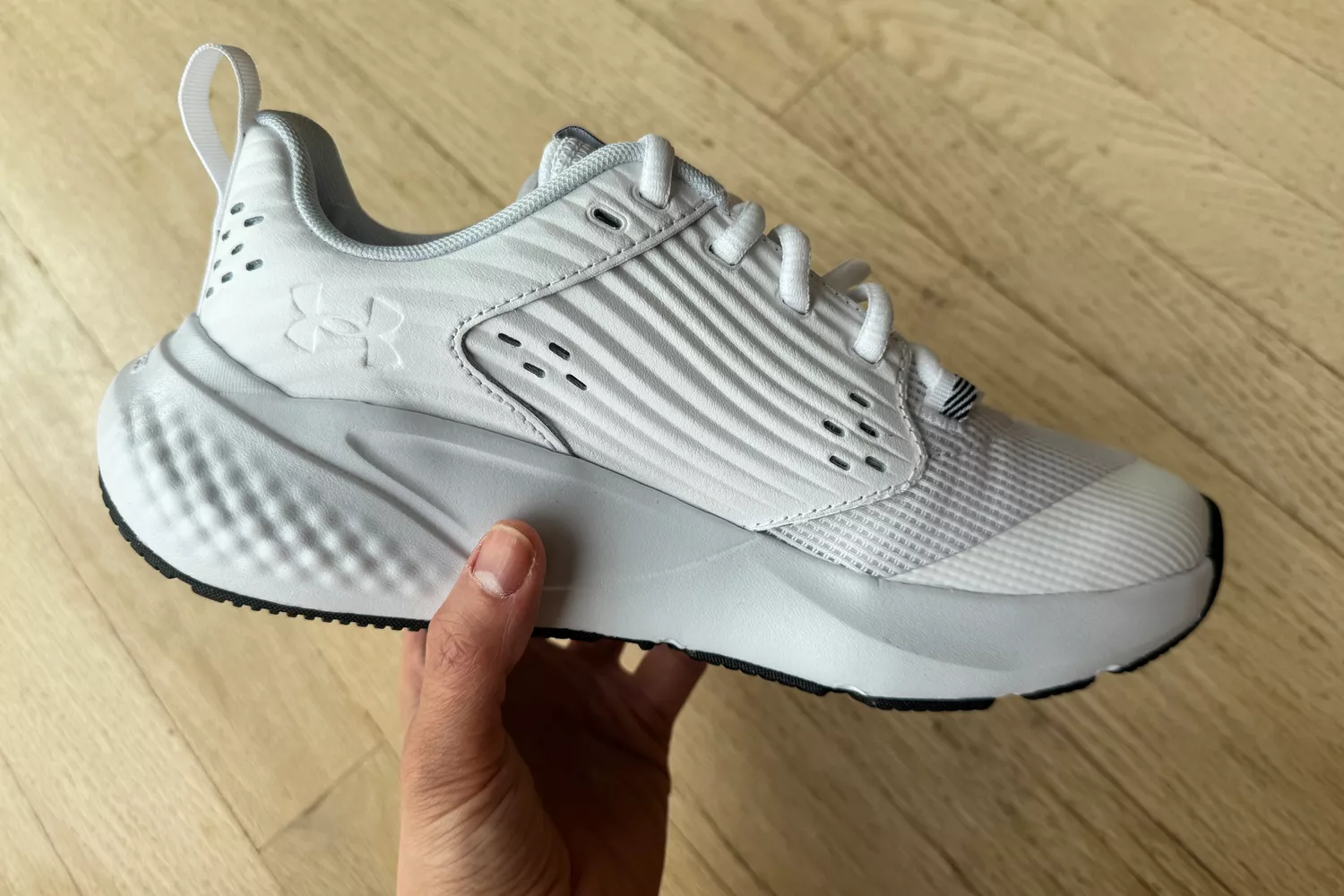 A person holds up the Under Armour Women's UA Commit 4 Training Shoe