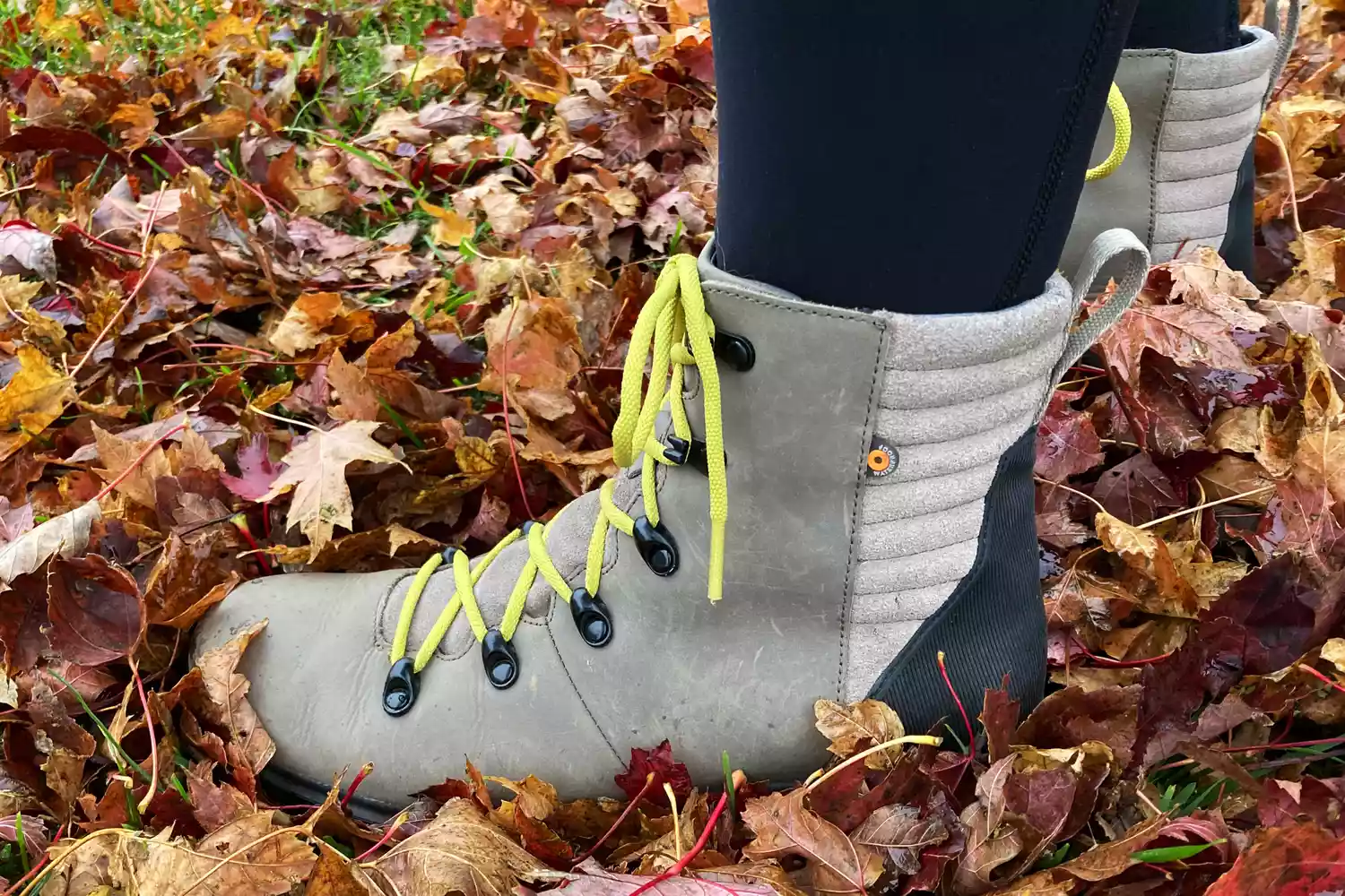 A person wearing Bogs Holly Lace Leather Boots standing on wet leaves