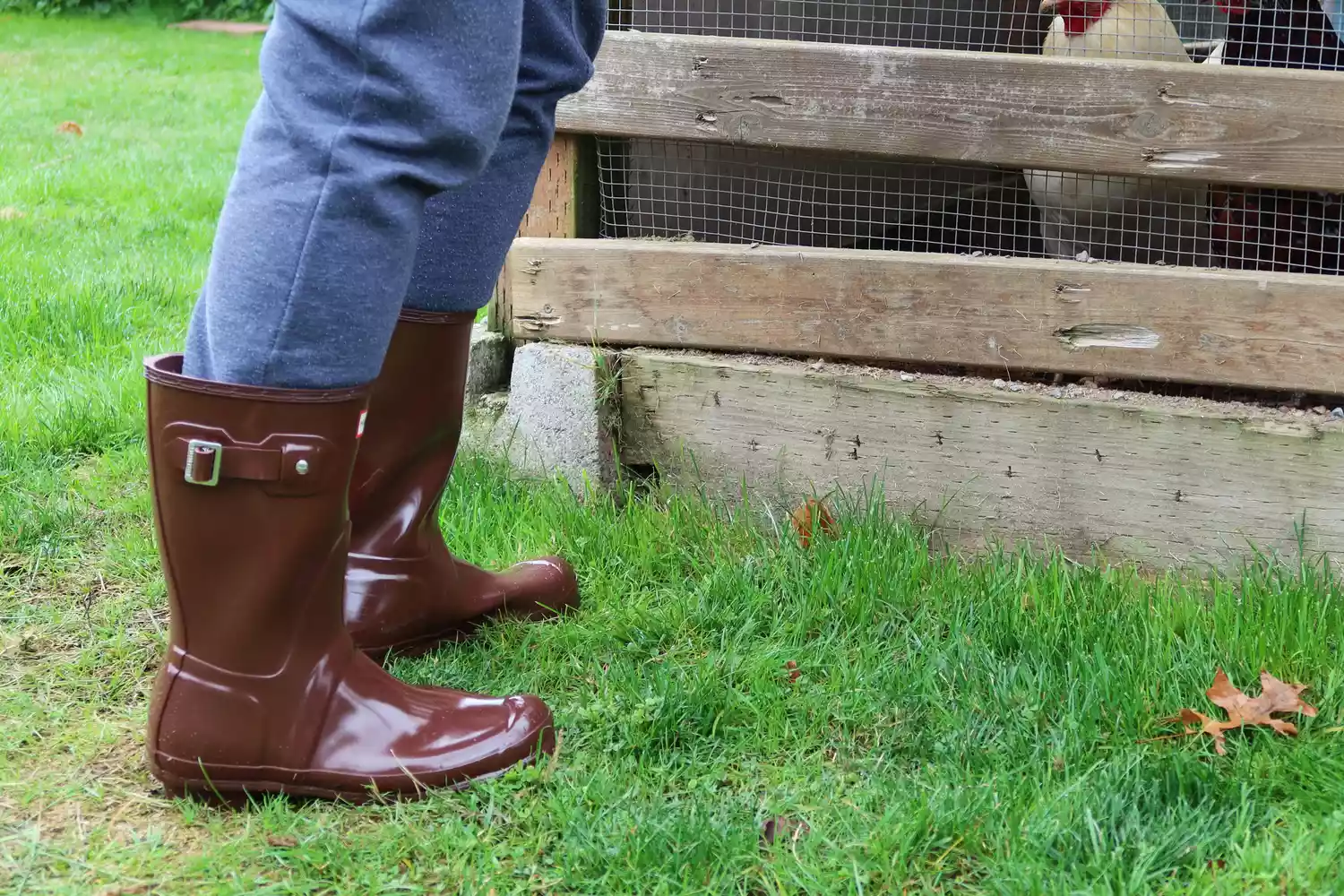 A person stands on grass wearing the Hunter Women's Original Short Rain Boots