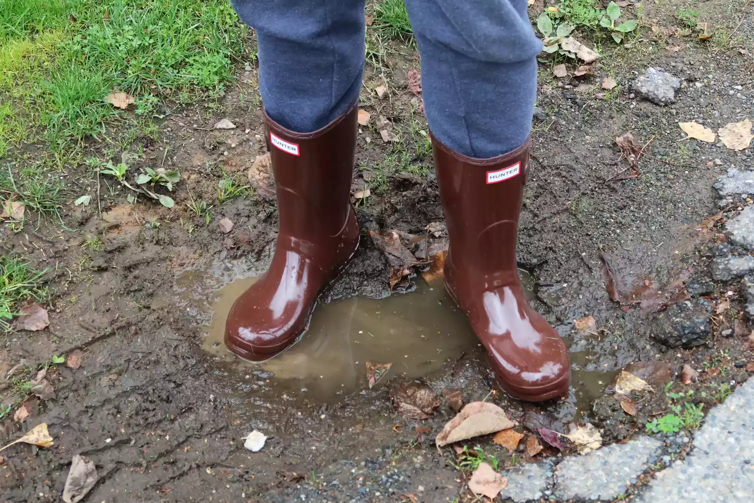 A person wearing in the Hunter Women's Original Short Rain Boots stands in a puddle
