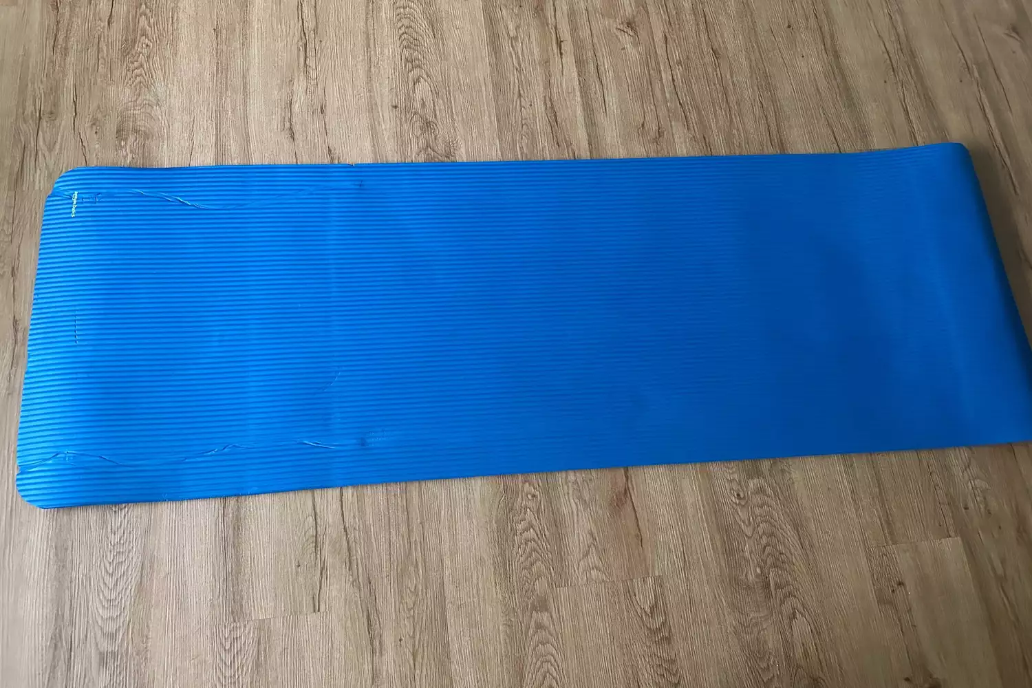 Amazon Basics 1/2-inch Extra Thick Exercise Yoga Mat unrolled on wooden floor