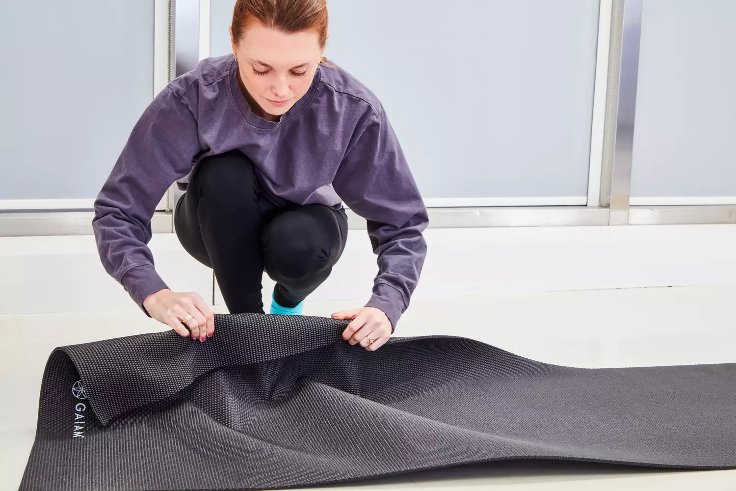 Woman folds over the corner of a Gaiam Classic Solid 5mm Yoga Mat