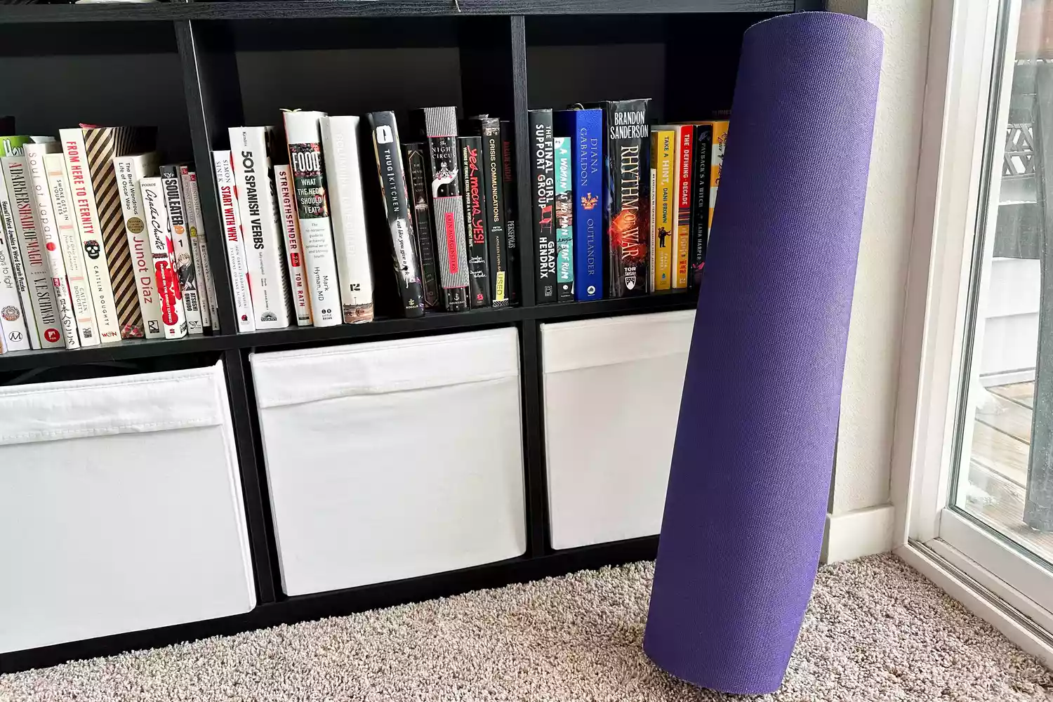 Jade Yoga XW Fusion Yoga Mat leaning against a book shelf