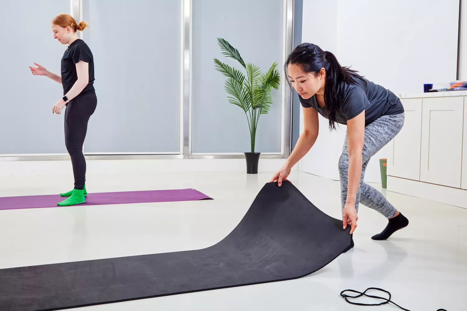 A woman holds the end of a Nike Training Mat 2.0