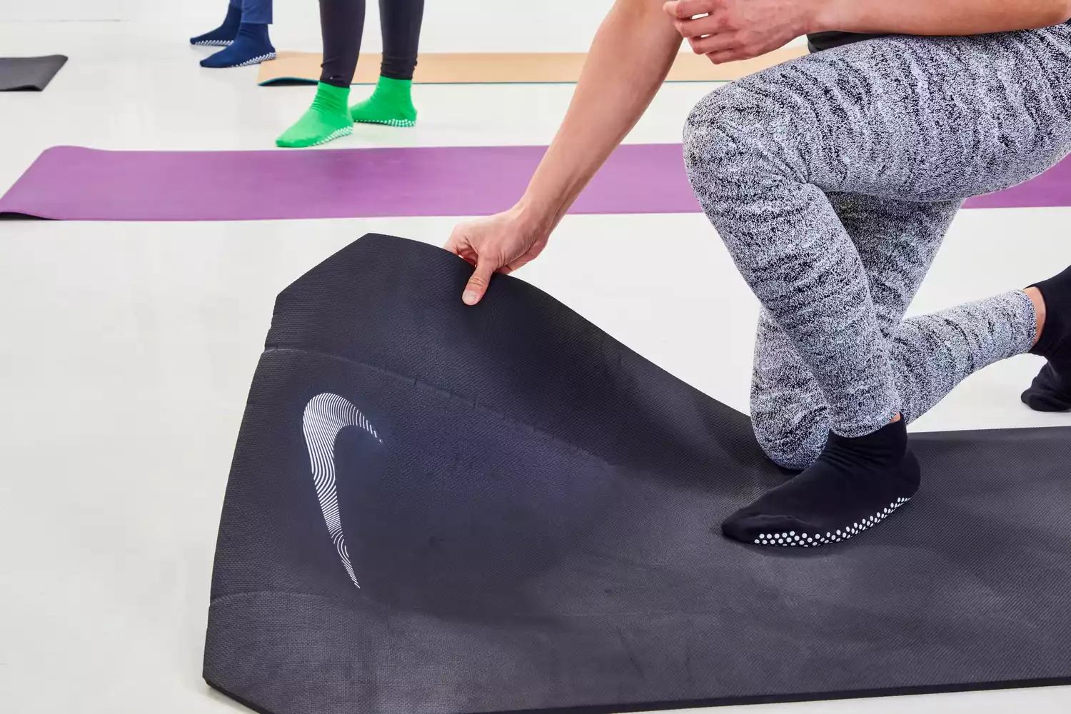 A person holds the corner of a Nike Training Mat 2.0
