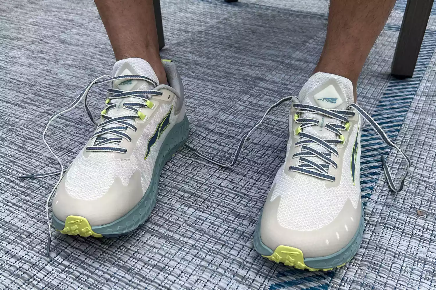 A close-up of a person wearing untied Altra Outroad 2 sneakers