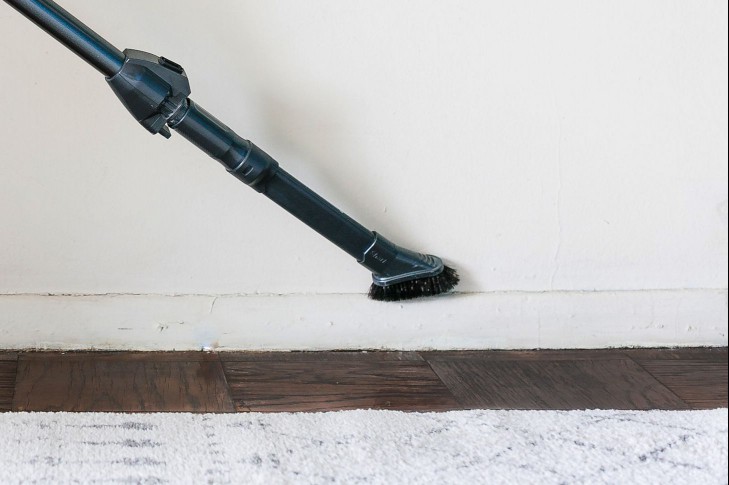 using the vacuum brush attachment on a baseboard