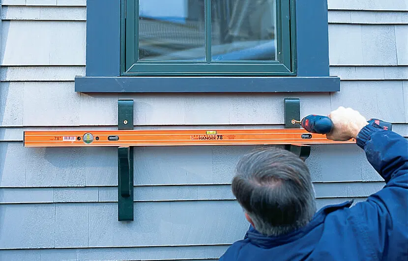 Silva installs the second window box bracket and makes sure they are level.