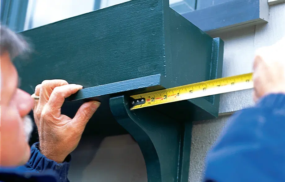 Silva hangs the window box on its brackets and makes sure it's level.