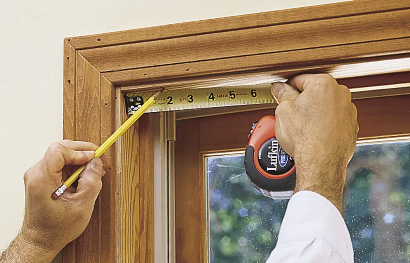 A pencil and measuring tape being used to mark bracket locations for window shades.