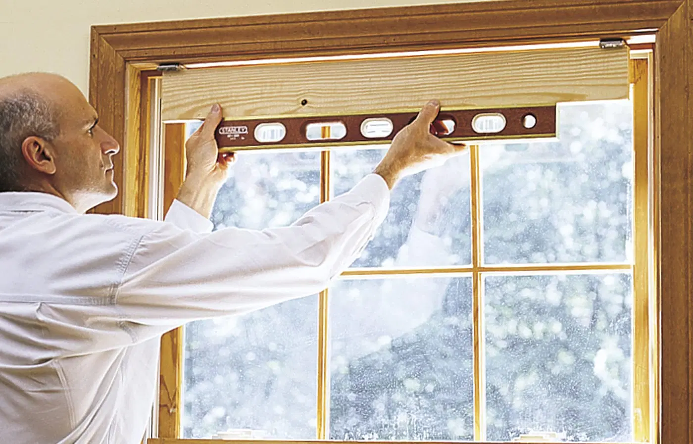 a level being used to check the placement of mounting brackets for window shades.