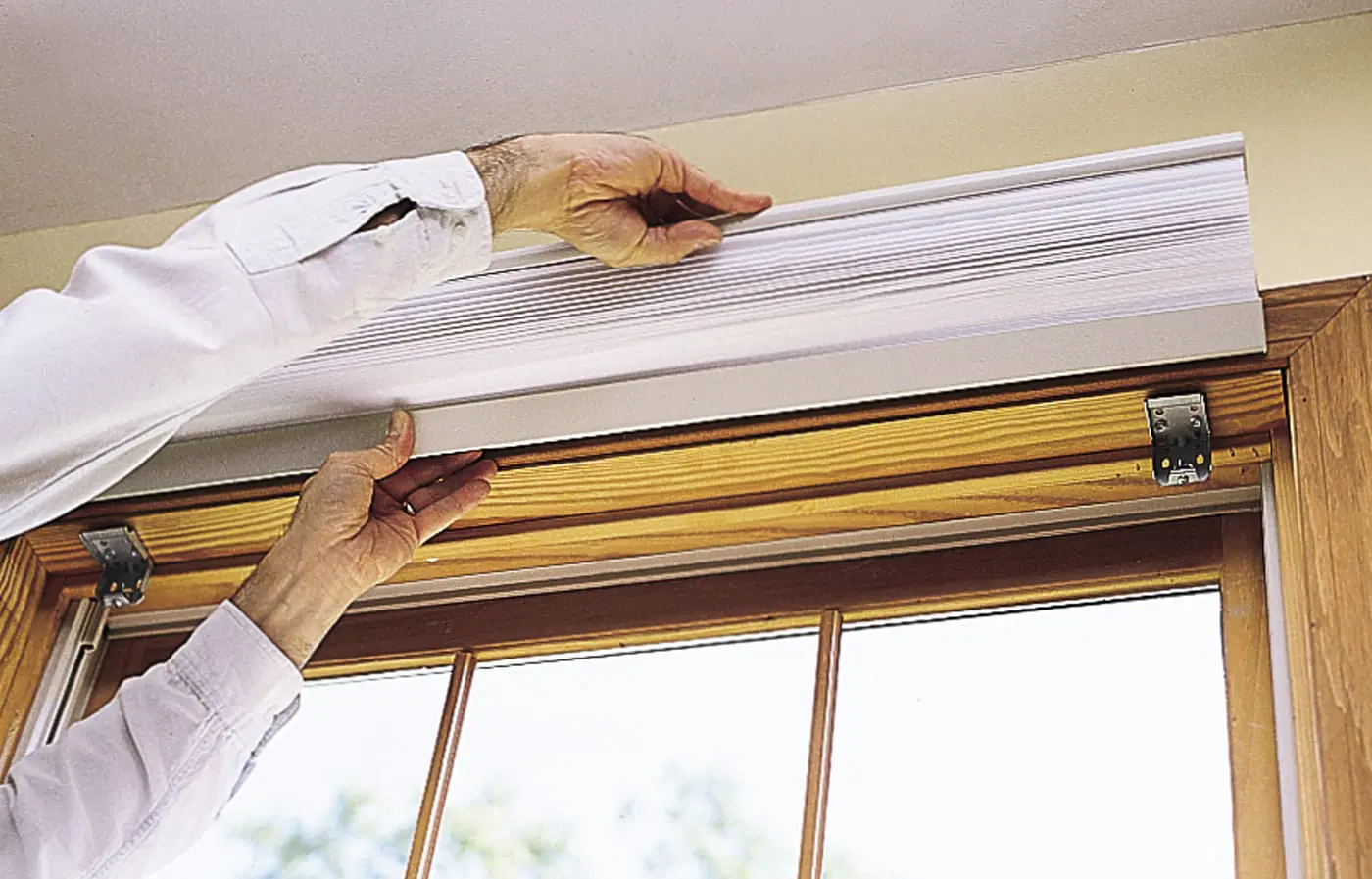 A window shade being clipped into it's mounting brackets.