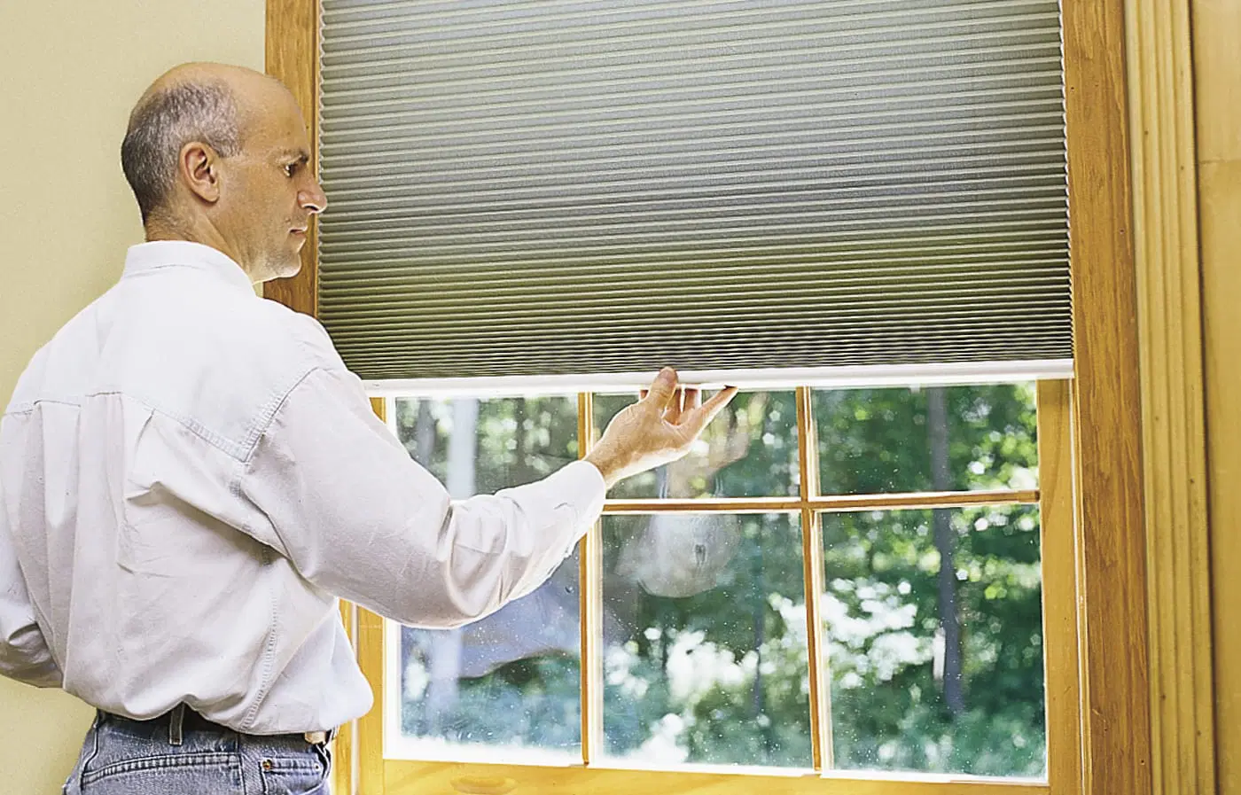 A man testing window shades to see that they are working properly.