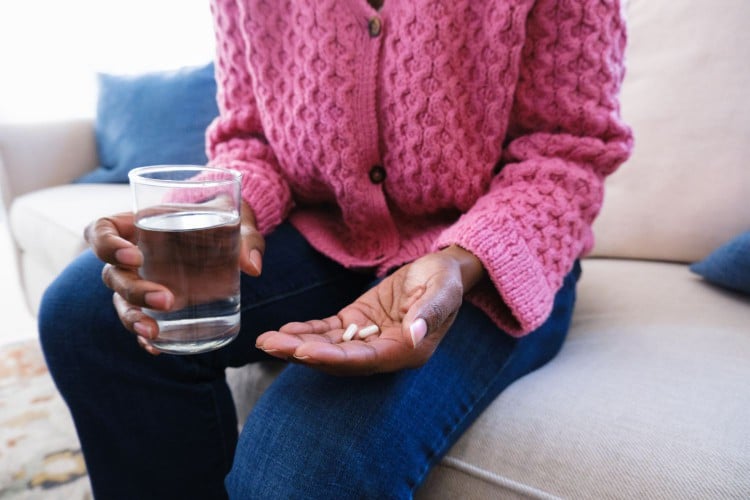 woman holding capsules/tablets and water.