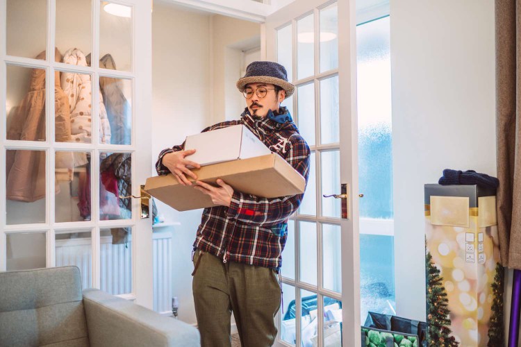 Man carrying boxes of things he's bought into his home