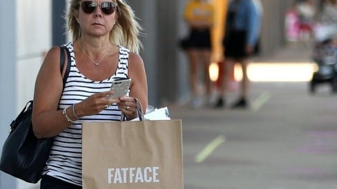 A shopper holds a Fat Face bag at Rushden Lakes outlet
