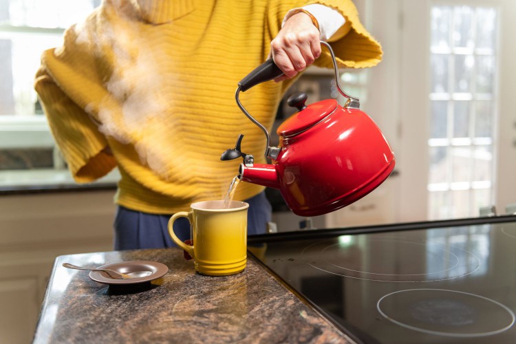 Woman pouring a hot kettle to make a cup of tea