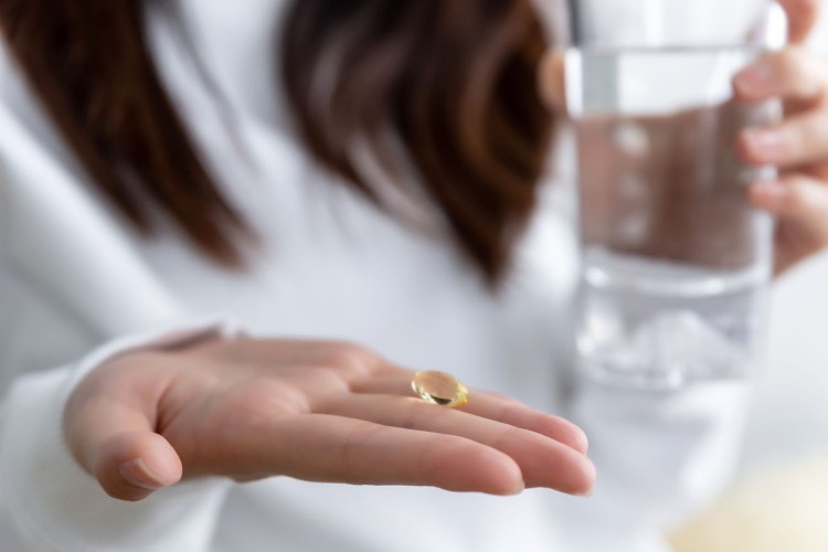 Woman taking a vitamin D capsule