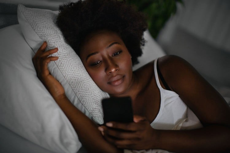 Young woman on her phone in bed
