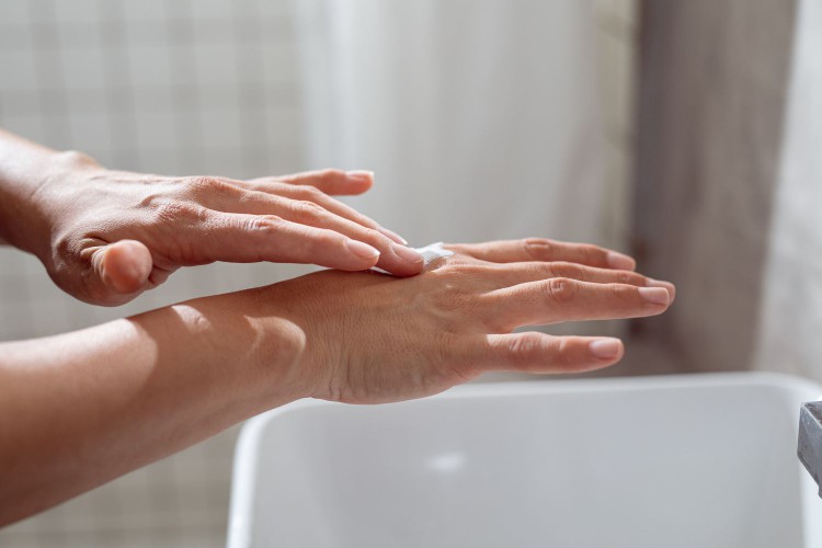 Woman putting lotion on her hands
