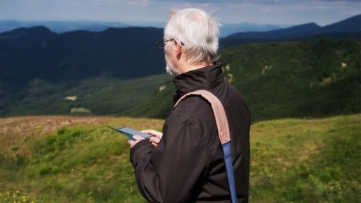 An older man stops while hiking to take in the view