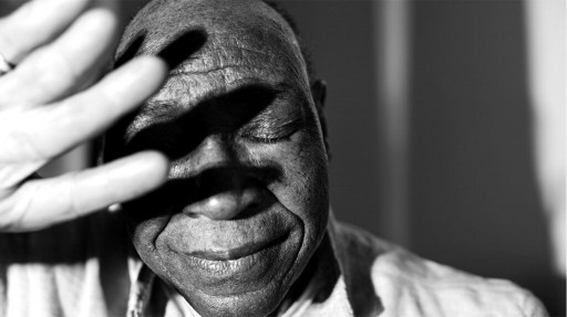 black and white photo of older Black man shielding his face with his hand