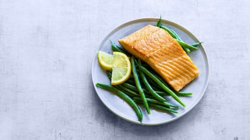A plate of salmon, green beans, and lemon